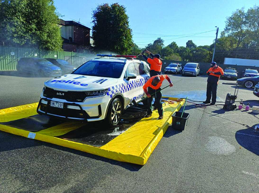C2A team washing a Victoria Police vehicle within a yellow portable wash mat