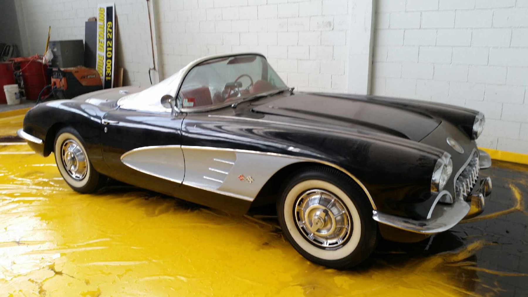 Classic car positioned on a yellow wash mat inside a vehicle wash area