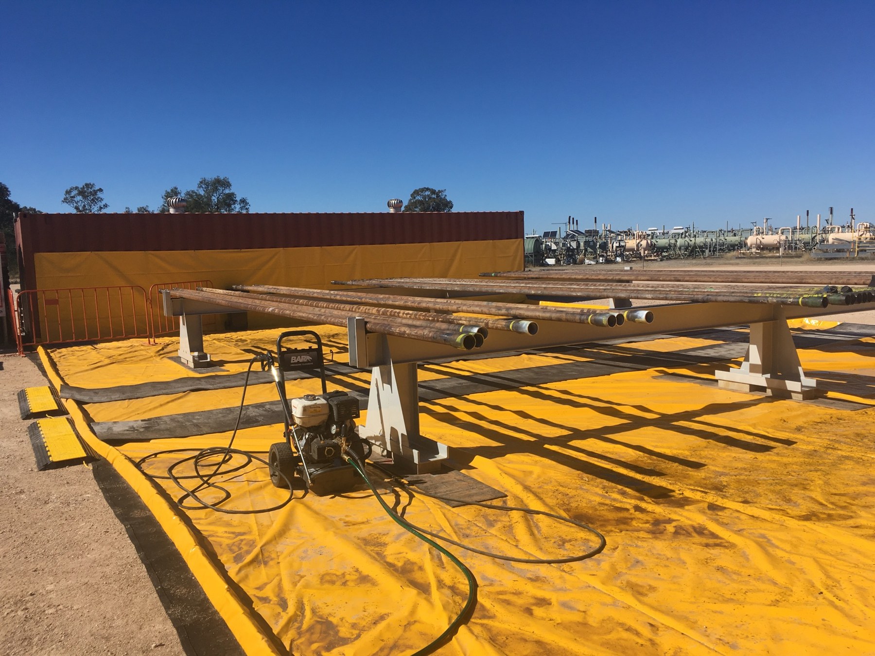 Yellow vehicle wash mat with washdown equipment at an outdoor project site